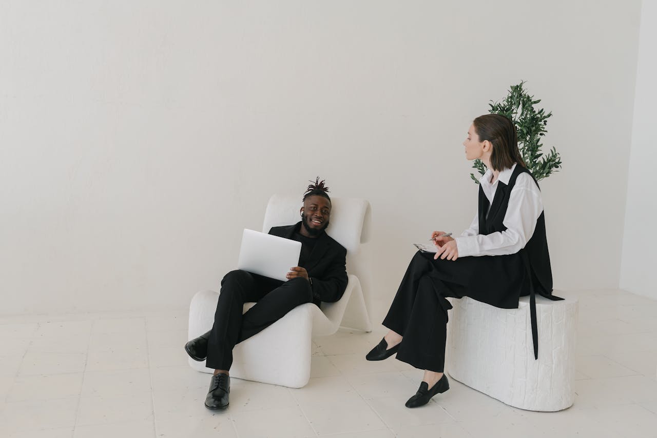 Business professionals engaged in a meeting within a minimalist studio setting with contemporary furniture.